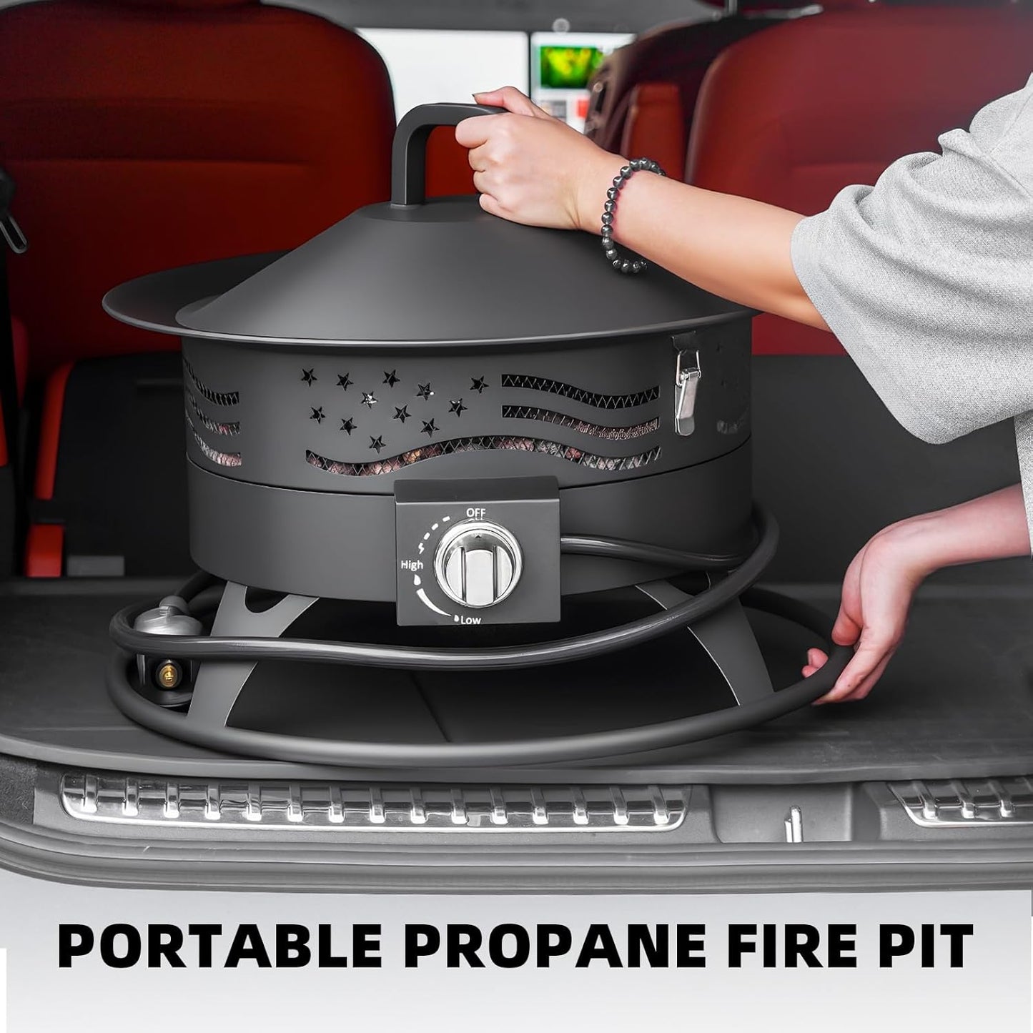 Black 20-inch round portable propane fire pit with grill grate and lava rocks glowing on a backyard patio at night