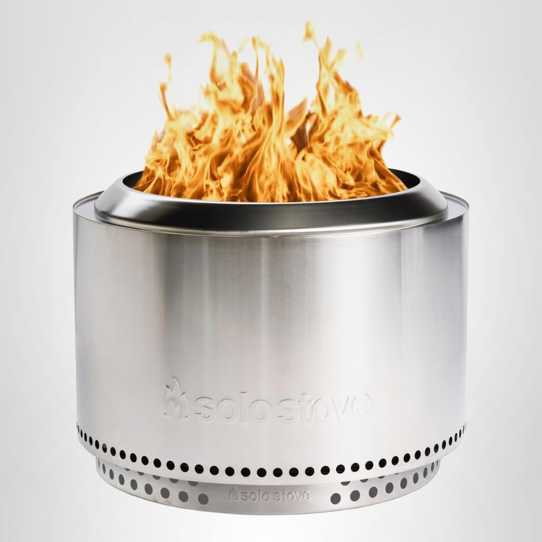 Solo Stove Yukon 2.0 stainless steel smokeless fire pit with stand glowing with a wood fire in a backyard at night