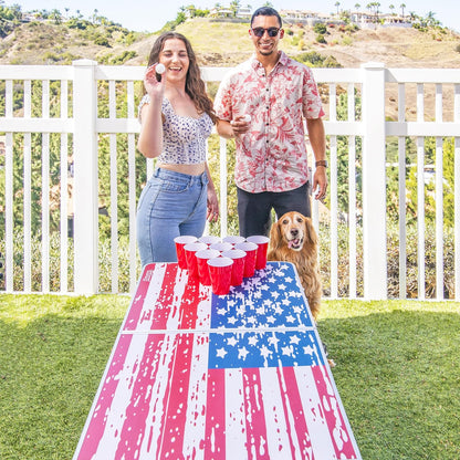 GoPong 8 foot portable beer pong and tailgate table in American Flag edition set up outdoors at a 4th of July backyard party